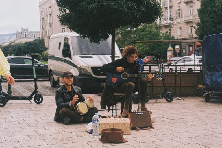 Another perspective of street musicians playing music in Tbilisi, Georgia. Captured on 35mm Kodak Gold 200 film with a vintage Nikon FE by Georgian artist Zurab Kostava, reflecting the atmosphere of the city.